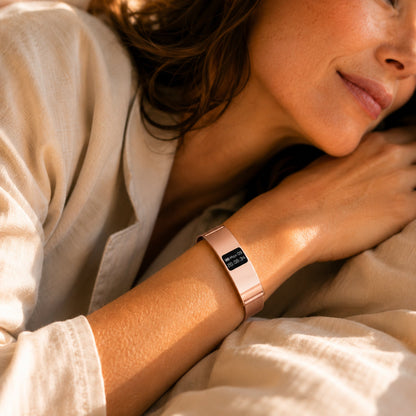 Close up of woman's wrist wearing the Slunix rose gold sleep band in bed, soft morning light lifestyle photography